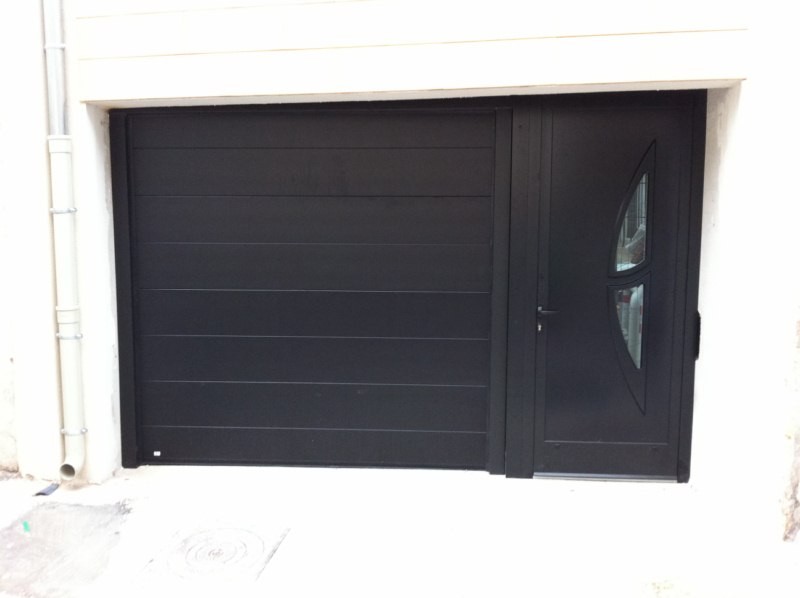 Porte de garage sectionnelle noire installée sur une villa
